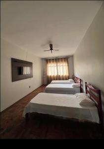 a bedroom with two beds and a ceiling at Apartamento 104 - Suíte econômica com ventilador in Patos de Minas