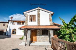 a small white house with a brown door at Istrska kamnita hiša z velikim vrtom - Istrian Stone House with Big Garden in Marezige +23 photos