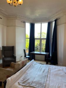 a bedroom with a bed and a desk and a window at Old style room near Singleton Hospital sleeps three in Swansea