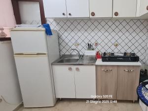 a small kitchen with a refrigerator and a sink at Casa vacanze Andry in Cinisi