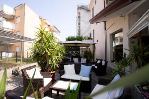 un patio avec des chaises blanches, des tables et des plantes dans l'établissement Hotel Berna, à Eraclea Mare