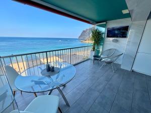 ein Balkon mit Tisch und Stühlen und dem Meer in der Unterkunft 1st line La Fossa Luxury Beach Apartment *ADULTS ONLY* in Calpe