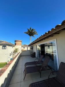 a patio with two chairs and a palm tree at Apartamento Exclusivo Búzios Centro in Búzios