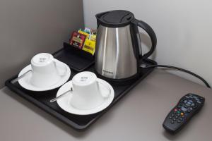 a tray with two cups and a coffee pot and a remote control at Leonardo Da Vinci Guest House in Rome