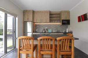 a kitchen with wooden chairs and a counter with a counter top at All Good in Rotorua +9 photos
