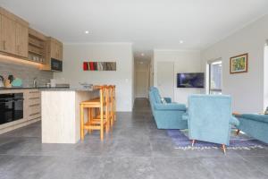 a kitchen and a living room with blue chairs at All Good in Rotorua