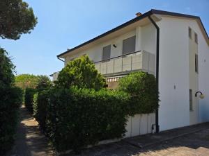 una casa blanca con arbustos delante en MareBlu Apartment with patio, en Marina di Castagneto Carducci