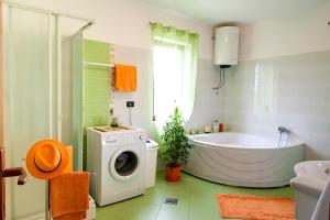 a bathroom with a tub and a washing machine at Apartman Orbanići in Orbanići