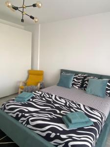 Un dormitorio con una cama con estampado de cebra y una silla amarilla. en Apartament modern cu balcon, en Bucarest