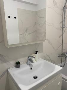 Un baño blanco con lavabo y espejo. en Apartament modern cu balcon, en Bucarest 12 fotos más