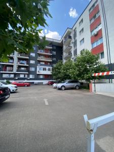 Un estacionamiento con autos estacionados frente a un edificio. en Apartament modern cu balcon, en Bucarest