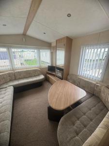 a living room with couches and a table and windows at 3 Bed Caravan - Sleeps 8 - Pets - Parking in Rhyl