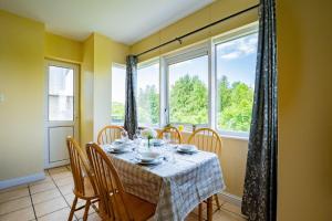 une salle à manger avec une table, des chaises et des fenêtres dans l'établissement Budget Friendly 3 Bed Apartment, à Galway