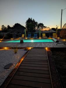 a swimming pool with lights in a backyard at night at L'échappée Huroise, piscine et spa privatifs in Hure