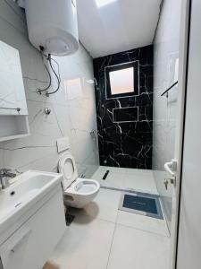 a white bathroom with a toilet and a sink at Rine Apartments in Ulcinj +8 photos