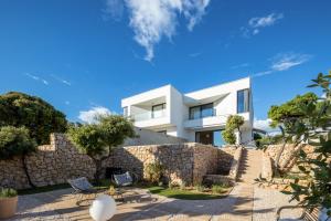 a house with a stone wall and two chairs at Vila Oliva i Terakota in Mandre