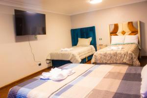 a hotel room with two beds and a flat screen tv at Hatun Wasi Puno in Puno +12 photos