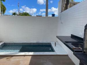 a swimming pool in a backyard with a tile wall at Casa Mar III in João Pessoa