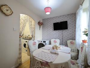 a dining room with a table and chairs and a tv at City Centre Vintage Theme Guest Rooms in Liverpool