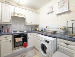 a kitchen with white cabinets and a washer and dryer at City Centre Vintage Theme Guest Rooms in Liverpool