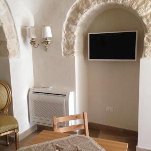 a room with a tv on a wall with a chair at Resort Romano in Trulli in Alberobello