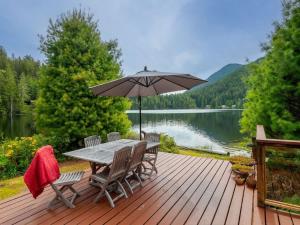 una terraza de madera con mesa, sillas y sombrilla en North Lake Waterfront Home, en Egmont