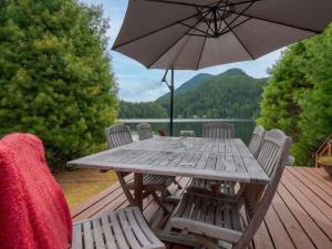 una mesa de madera con sillas y una sombrilla en una terraza en North Lake Waterfront Home, en Egmont