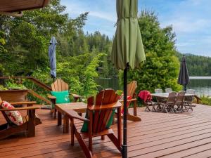 una terraza de madera con sillas y sombrilla en North Lake Waterfront Home, en Egmont