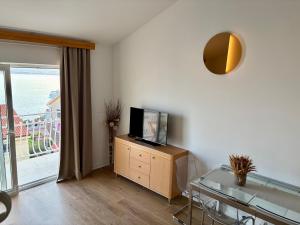 a living room with a television on a dresser with a glass table at Apartment Araucaria Gallery in Crikvenica