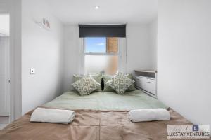 a bedroom with a bed with pillows and a window at City Centre - Top Floor Luxury Apartment - Free Secure Small Car Parking - 5 Minute Walk to Beach & Station in Brighton & Hove