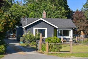 a house with a fence in front of it at The Bayside Cottage by EMR Vacation Rentals in North Saanich