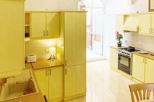 a kitchen with yellow cabinets and a stove top oven at Bougainvillea Breeze & Marina View - Happy Rentals in Cospicua