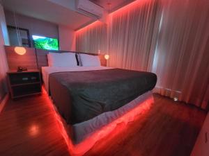 a bedroom with a bed with red lights on it at Suíte Las Vegas, Tv 55" Barra da Tijuca, Riocentro in Rio de Janeiro