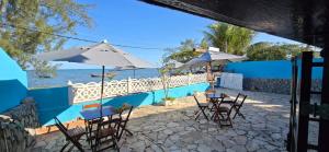 a patio with tables and umbrellas and the ocean at Pousada Casa Del Mare in São Pedro da Aldeia