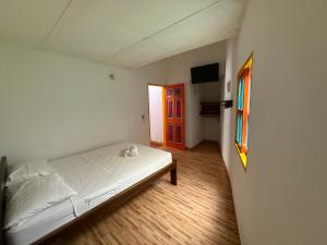 Un dormitorio con una cama blanca y una puerta roja. en Hostería El Paraíso, en Jardín 14 fotos más