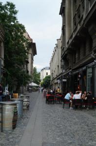 a cobblestone street with people sitting at tables in chairs at Bucarest old center in Văleni
