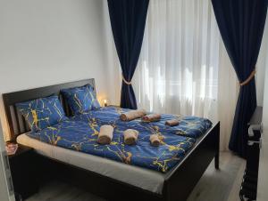 a bed with a blue comforter and some pillows at Bucarest old center in Văleni