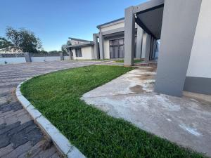 a house with a grassy yard next to a building at Mercy Accommodation Guest House in Jwaneng