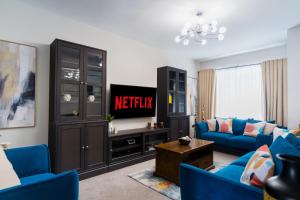 a living room with blue couches and a tv at Dublin Premier Homestay in Ráth Cúil