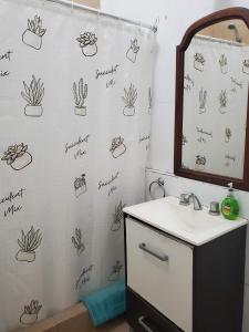 Un baño con una cortina de ducha con dibujos de cactus. en Casa de Invitados 2, en Pergamino