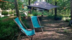 two lawn chairs and an umbrella in the shade at Tentes suspendues D'En Haut in Friaudour