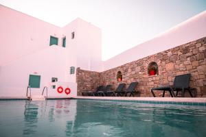 a swimming pool with chairs next to a building at Celeste Apartments in Ornos