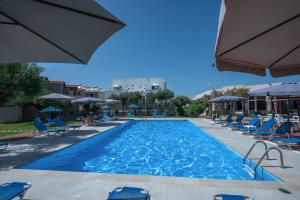 a large swimming pool with blue chairs and umbrellas at Creteco Hotel & Suites in Gournes
