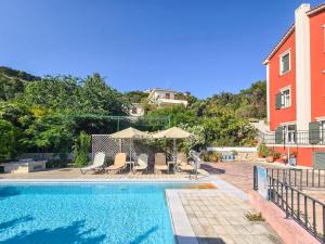 a swimming pool with chairs and umbrellas next to a building at Liogerma Art Deco Villa - 5 min drive to Lassi in Sarláta