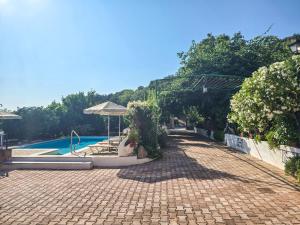 a brick walkway next to a swimming pool with an arbor and a swimming at Liogerma Art Deco Villa - 5 min drive to Lassi in Sarláta