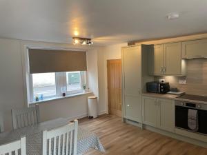 a kitchen with a table and a microwave and a window at Central Kirkwall House in Orkney