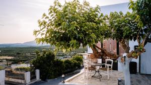 a table and chairs on a balcony with a tree at Evnia Sunset Crete Escape, Private HotTub Retreat in Rotásion