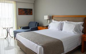 a bedroom with a bed and a blue chair at Hotel Estelar Altamira in Ibagué