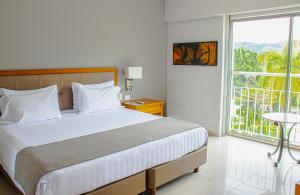 a bedroom with a bed and a large window at Hotel Estelar Altamira in Ibagué