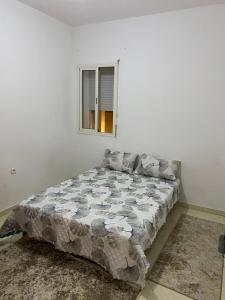 un lit dans une chambre blanche avec une fenêtre dans l'établissement Appartement à Skhirat, à Skhirat